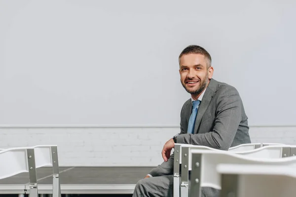 Bonito sorridente empresário sentado na cadeira no cubo — Fotografia de Stock