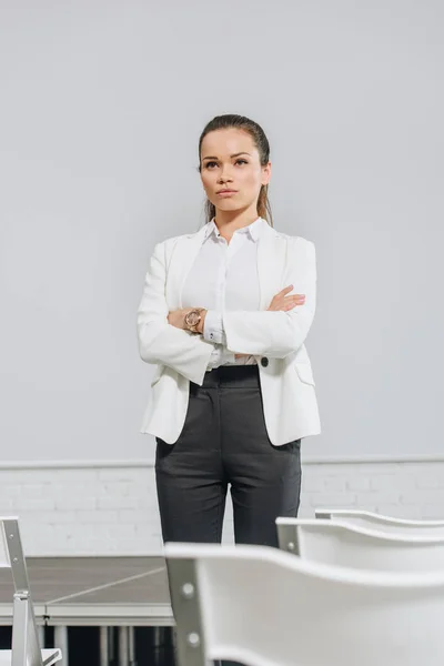 Attractive serious businesswoman standing with crossed arms in hub — Stock Photo