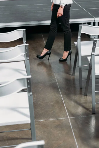 Imagen recortada de la mujer de negocios caminando entre el escenario y las sillas en el centro - foto de stock