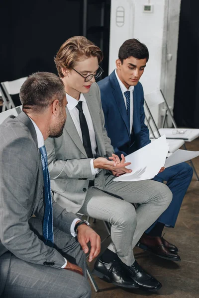 Homens de negócios sentados em cadeiras durante a formação e falando sobre documentos em hub — Fotografia de Stock