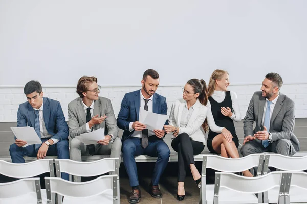 Businesspeople sitting with documents on stage and talking in hub — Stock Photo