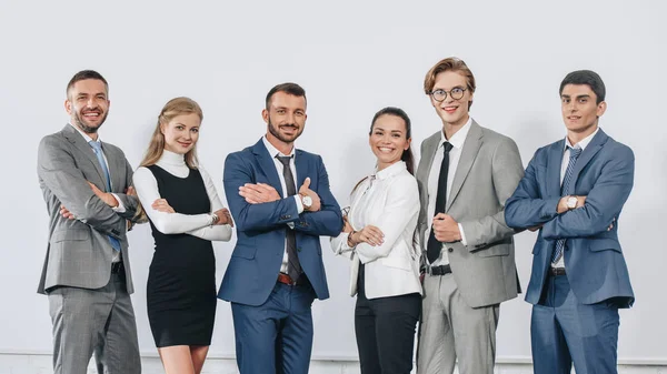 Smiling businesspeople with crossed arms posing near board after training in hub and looking at camera — Stock Photo