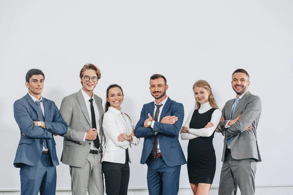 Empresarios sonrientes con brazos cruzados posando cerca de la tabla después de entrenar en el hub - foto de stock