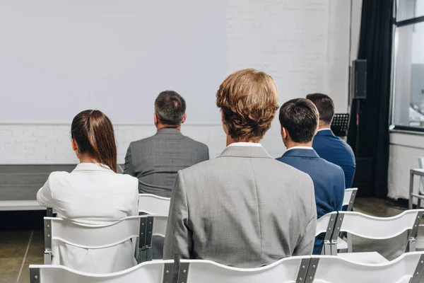 Back view of businesspeople sitting on chairs at training in hub — Stock Photo