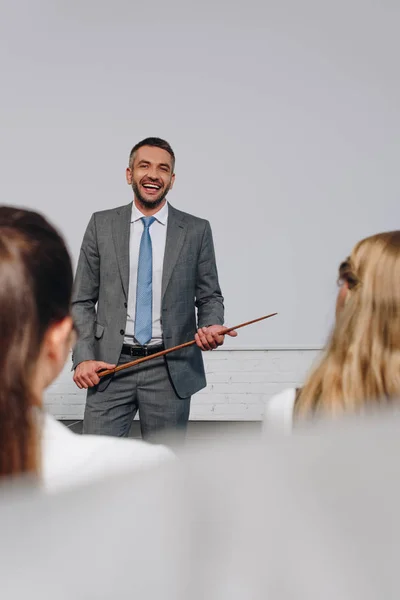 Rindo bonito treinador de negócios segurando vara ponteiro durante o treinamento no hub — Fotografia de Stock