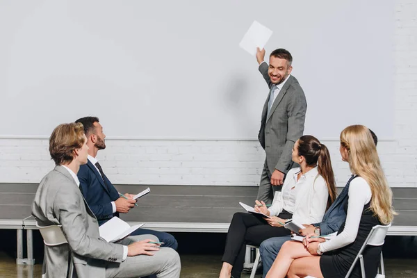 Smiling business coach pointing on board during training in hub — Stock Photo