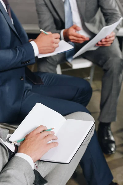 Immagine ritagliata di uomini d'affari che scrivono qualcosa per notebook durante la formazione in hub — Foto stock