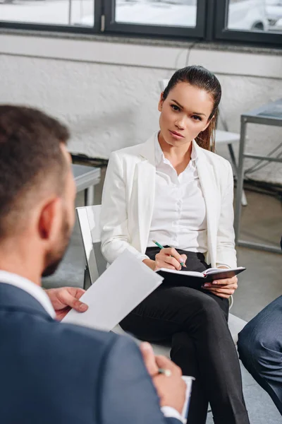 Beautiful business coach looking at businessman at training in hub — Stock Photo