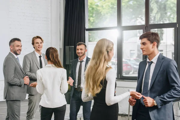 Young professional businesspeople standing and talking in hub — Stock Photo