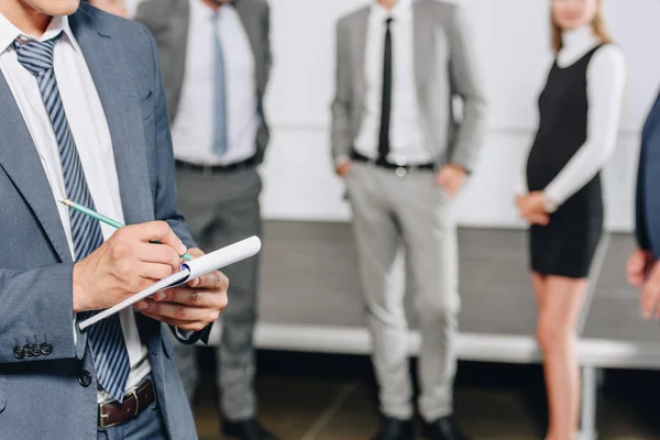 Abgeschnittenes Bild eines Geschäftsmannes, der mit Bleistift in der Nabe etwas zu Notizbuch schreibt — Stockfoto