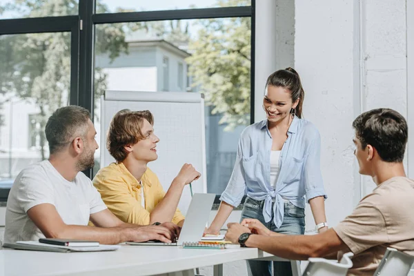 Uomini d'affari seduti a tavola durante la riunione e guardando la donna d'affari in carica — Stock Photo