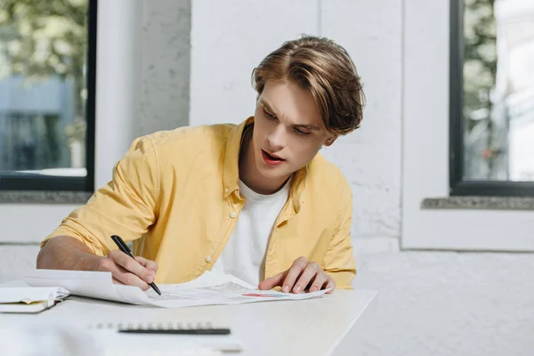 Guapo hombre de negocios escribiendo algo a documentos en la oficina - foto de stock