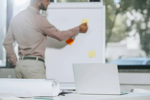 Imagen recortada de hombre de negocios que se prepara para la reunión en la oficina con el ordenador portátil en primer plano - foto de stock