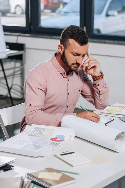 Tired pensive businessman writing something in office — Stock Photo