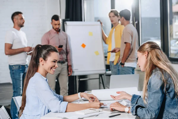 Усміхнені бізнесмени дивляться на документи під час зустрічі в офісі — стокове фото
