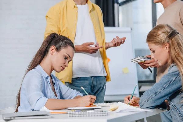 Imagen recortada de las empresarias escribiendo algo durante la reunión en la oficina - foto de stock