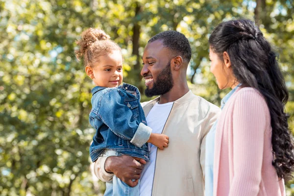 Ritratto di felici genitori afro-americani e figlia in piedi insieme nel parco — Foto stock