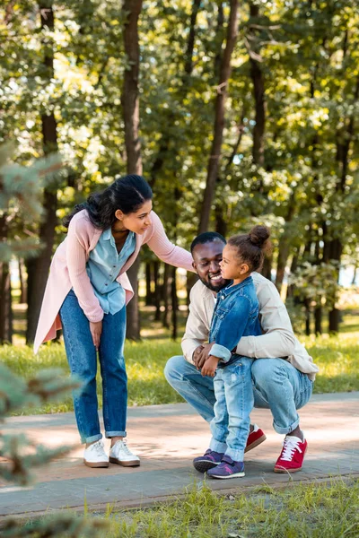Afroamericanos padres mirando a hija en camino en parque - foto de stock