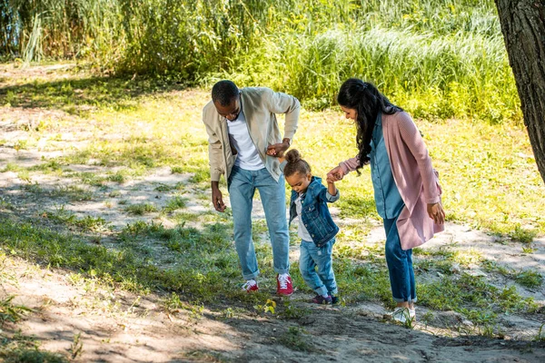 Afro-americanos pais e filha de mãos dadas e andando na colina no parque — Fotografia de Stock