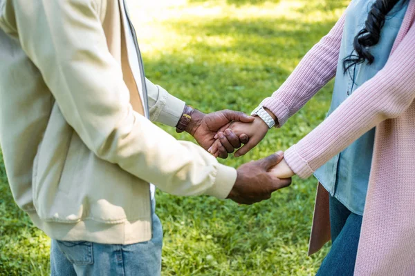 Обрезанное изображение африканской американской пары, держащейся за руки в парке — стоковое фото