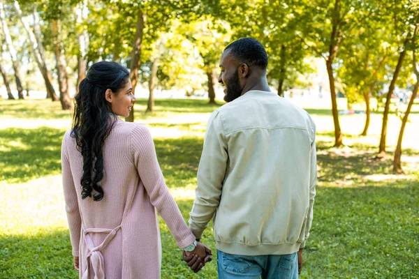 Африканская американская пара держатся за руки и смотрят друг на друга в парке — стоковое фото