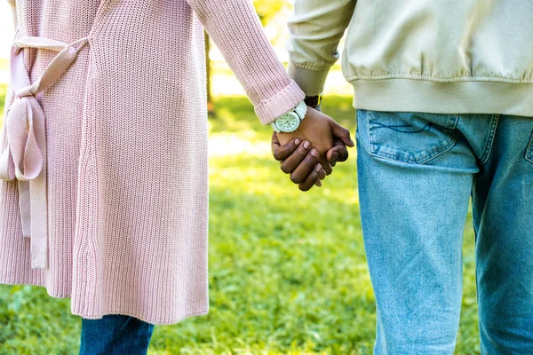 Обрезанное изображение африканской американской пары, держащейся за руки в парке — стоковое фото