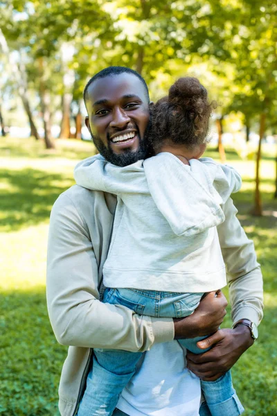 Feliz pai americano africano abraçando filha no parque — Fotografia de Stock