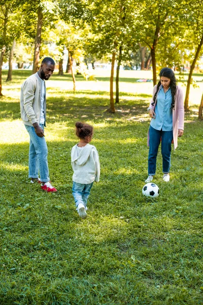 Afroamericanos padres e hija jugando fútbol juntos en parque - foto de stock