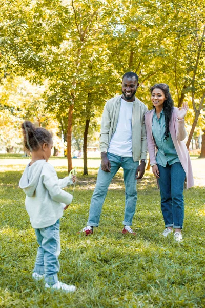 Feliz afroamericano madre saludando mano a hija en parque - foto de stock