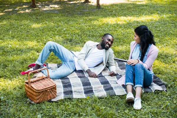 Africano casal americano olhando uns para os outros no piquenique no parque — Fotografia de Stock