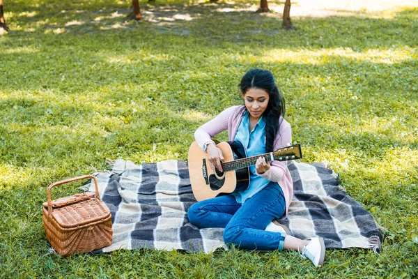 Attractive african american woman playing acoustic guitar at picnic in park — Stock Photo