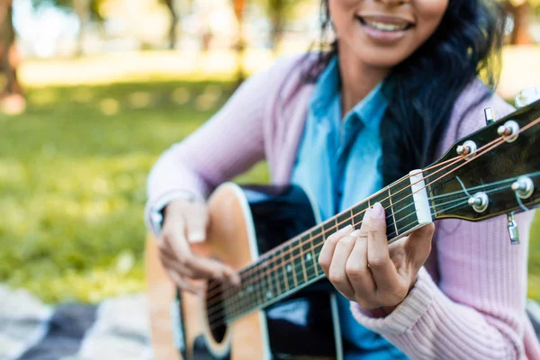 Imagen recortada de mujer afroamericana tocando la guitarra acústica en el parque - foto de stock