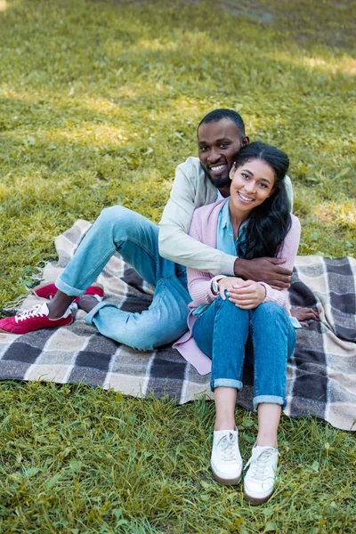 Vue grand angle de sourire copain afro-américain étreignant petite amie dans le parc — Photo de stock