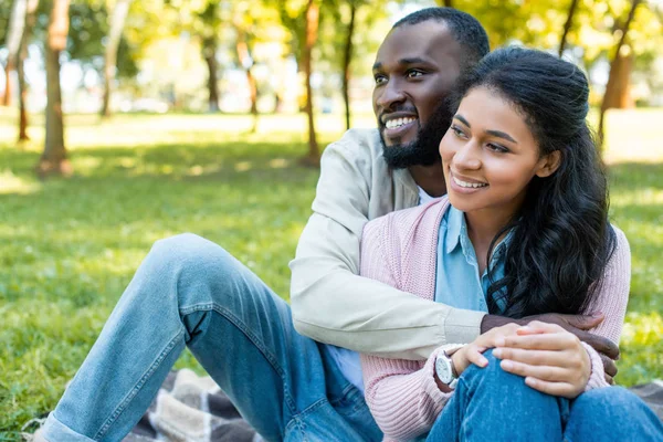 Sonriente afroamericano novio abrazando novia en parque - foto de stock