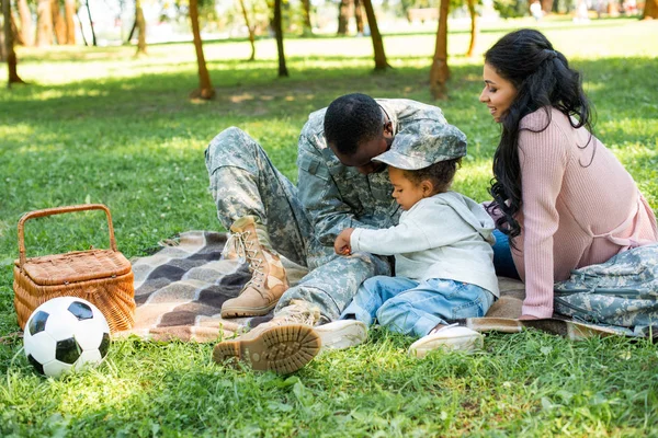 Soldado afroamericano en uniforme militar pasar tiempo con la familia en el picnic en el parque - foto de stock