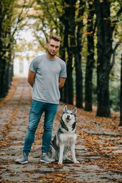 Young man with siberian husky dog in autumn park — Stock Photo