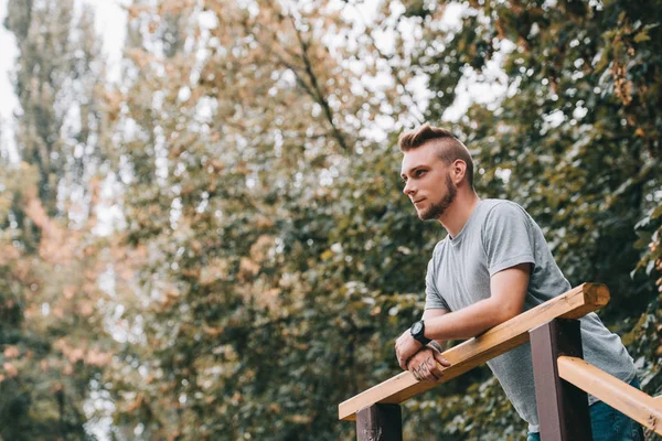 Schöner nachdenklicher Mann lehnt an Geländer im Park — Stockfoto
