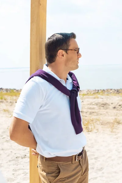 Uomo pensieroso in occhiali guardando lontano sulla spiaggia di sabbia — Foto stock