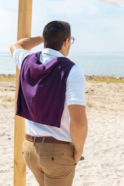 Vue arrière de l'homme regardant loin sur la plage de sable — Photo de stock