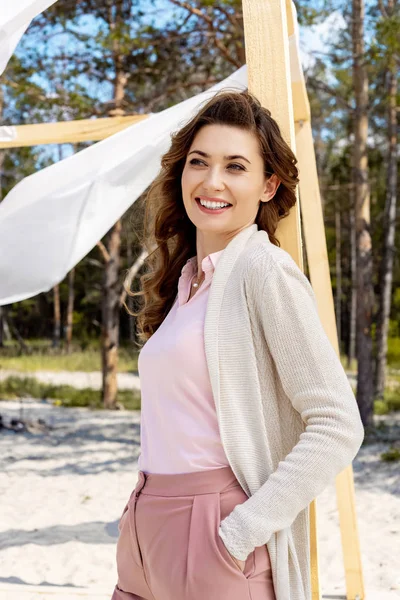 Ritratto di donna sorridente in piedi vicino alla decorazione in legno con pizzo tenda bianca — Foto stock