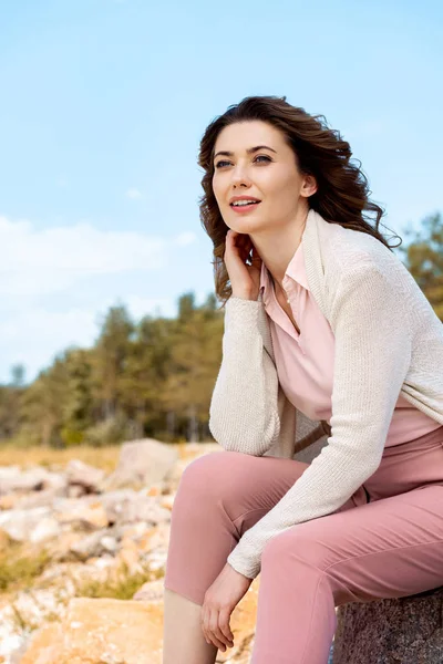 Attractive woman resting on rocks on sandy beach — Stock Photo