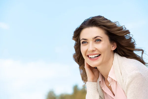 Portrait of smiling beautiful woman with blue cloudy sky on background — Stock Photo