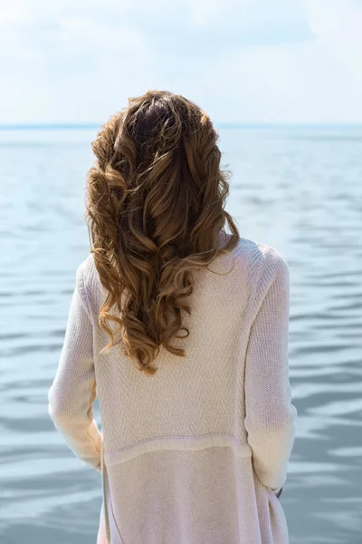 Vue arrière de la femme avec belle coiffure regardant la mer — Photo de stock