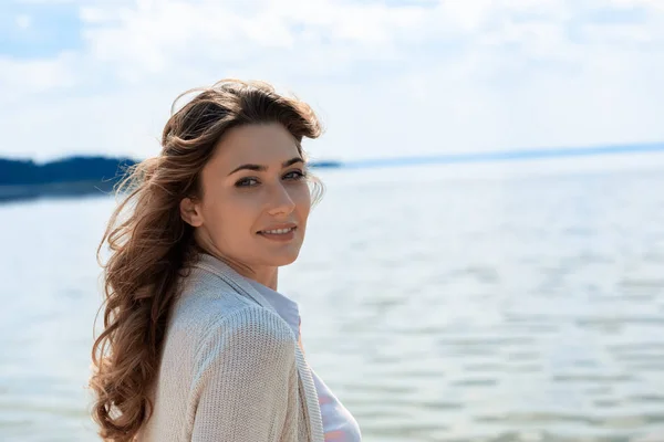 Vue latérale de belle femme regardant caméra avec rivière sur fond — Photo de stock