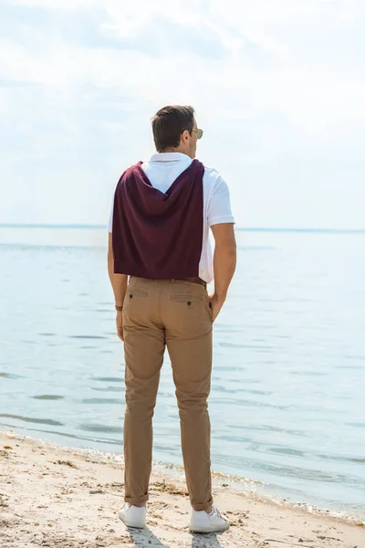 Back view of stylish man standing on sandy riverbank alone — Stock Photo