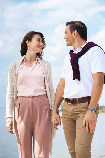 Portrait of couple in love holding hands and looking at each other on beach — Stock Photo