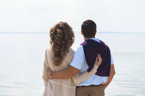 Vue arrière de couple romantique étreignant et regardant la mer — Photo de stock