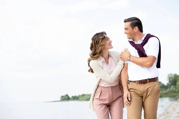 Porträt eines lächelnden Paares, das sich am Sandstrand anschaut — Stockfoto