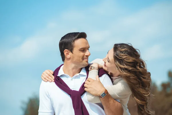 Porträt eines fröhlichen Paares, das einander mit blauem Himmel vor dem Hintergrund betrachtet — Stockfoto