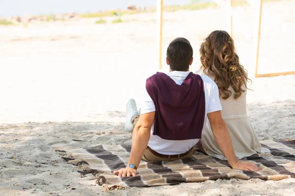 Вид на пару, отдыхающую на одеяле на песчаном пляже — стоковое фото